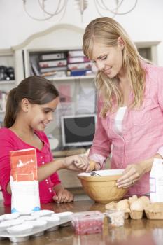 Mother And Daughter Preparing Ingredients To Bake Cakes In Kitchen
