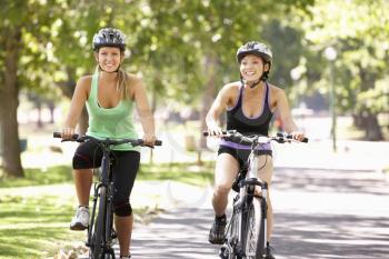 Two Women Cycling Through Park