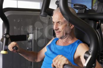 Middle Aged Man Using Weights Machine In Gym