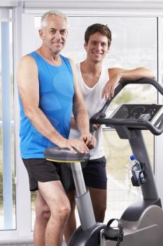 Portrait Of Middle Aged Man With Personal Trainer In Gym