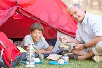 Grandfather And Grandson Cooking Breakfast On Camping Holiday