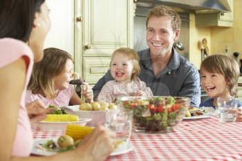 Family Eating Meal Together In Kitchen