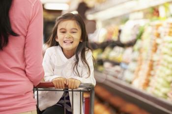 Close Up Of Mother Pushing Daughter In Supermarket Trolley