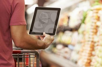 Close Up Of Man Reading Shopping List From Digital Tablet In Supermarket