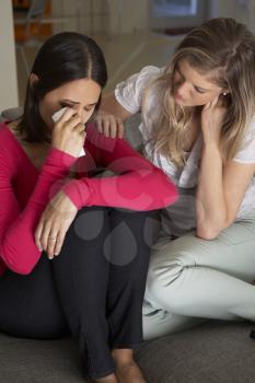 Woman Sitting On Sofa Comforting Unhappy Friend