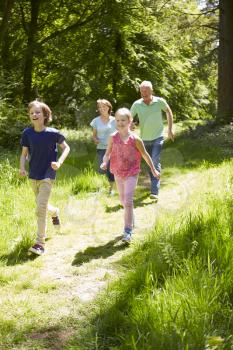 Grandparents With Grandchildren Running Through Countryside