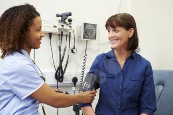 Nurse Taking Female Patient's Blood Pressure In Hospital