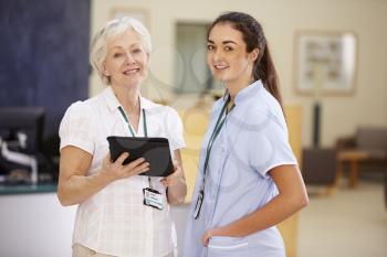 Female Consultant In Meeting With Nurse Using Digital Tablet