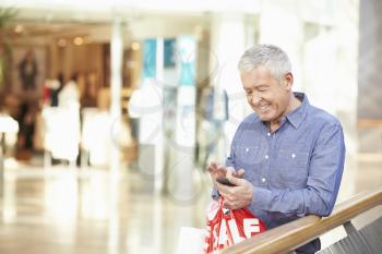 Senior Man In Shopping Mall Using Mobile Phone