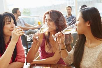 Three Female Friends Enjoying Drink At Outdoor Rooftop Bar