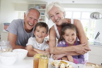 Grandparents With Grandchildren Eating Breakfast In Kitchen