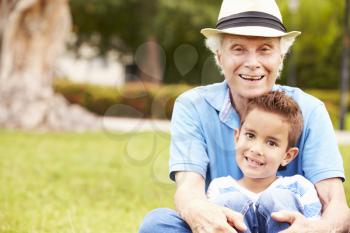 Grandfather And Grandson Sitting In Park Together