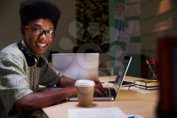 Office Worker With Coffee At Desk Working Late On Laptop