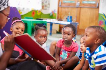 Teacher reading a book with a class of preschool children