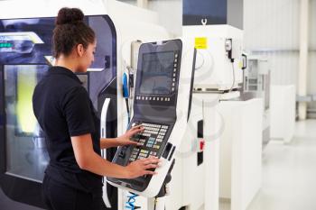 Female Engineer Operating CNC Machinery On Factory Floor