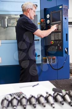 Male Engineer Operating CNC Machinery On Factory Floor