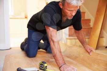 Man laying wood panel flooring during a house refurbishment