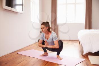 Woman Doing Yoga Fitness Exercises On Mat In Bedroom