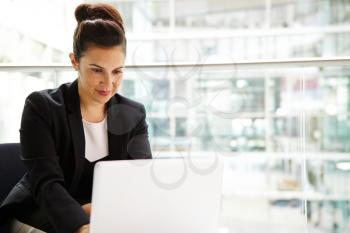Businesswoman using computer in modern interior, waist up