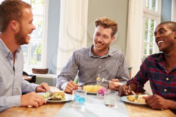 Male Friends At Home Sitting Around Table For Dinner Party