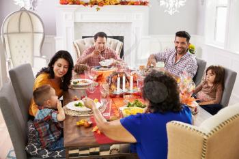 Family With Grandparents Enjoying Thanksgiving Meal At Table