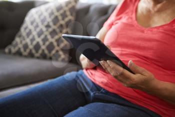 Close Up Of Senior Woman On Sofa Using Digital Tablet