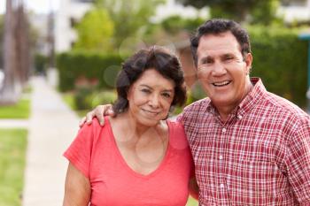 Senior Hispanic Couple Walking Along Sidewalk Together