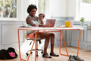 Woman holding child using computer at home after exercising