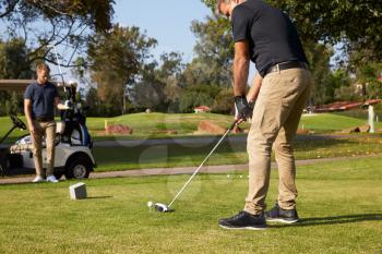 Male Golfer Lining Up Tee Shot On Golf Course