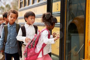 Elementary school kids climbing on to a school bus