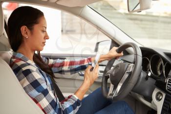 In car view of Hispanic female driver using phone