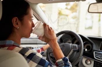 Close-up of Hispanic female driver drinking coffee in car