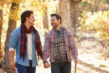 Gay Male Couple Walking Through Fall Woodland Together