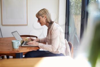 Woman Working From Home On Laptop In Modern Apartment