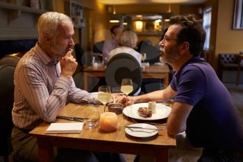 Middle aged male couple having evening meal in a restaurant