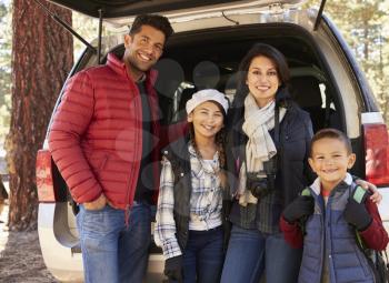 Portrait family outdoors standing at the open back of car