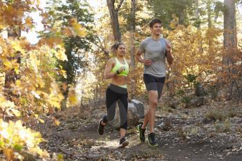 Caucasian woman and man running on a forest trail