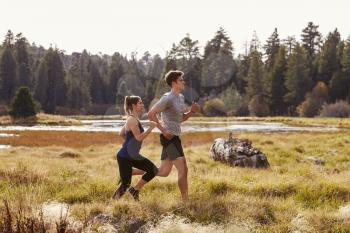Man and woman running in nature near a lake, close up