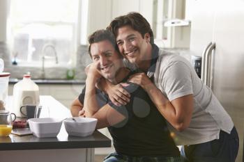 Male gay couple embracing in their kitchen, side view