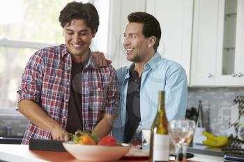 Male gay couple preparing a meal consult a digital tablet