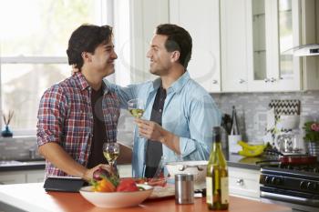 Smiling male gay couple drinking wine while preparing a meal