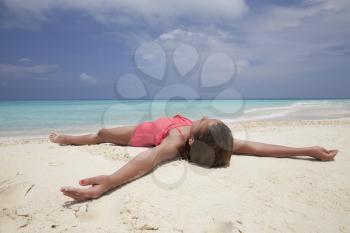 Young girl lying on a white sand beach by the ocean