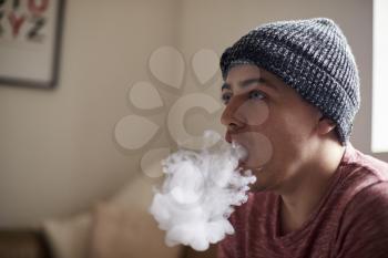 Young Man Exhaling Whilst Using Vapourizer