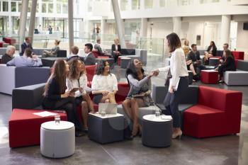 Businesswomen Meeting In Busy Lobby Of Modern Office