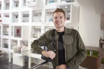 Young adult male student smiling on mezzanine in university