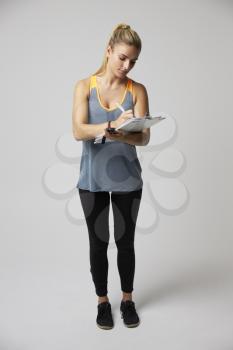 Studio Portrait Of Female Sports Coach With Clipboard