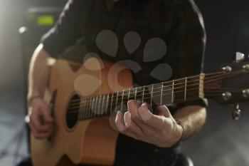 Close Up Of Man Playing Acoustic Guitar In Studio