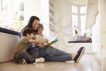 Mother And Sons Reading Story At Home Together