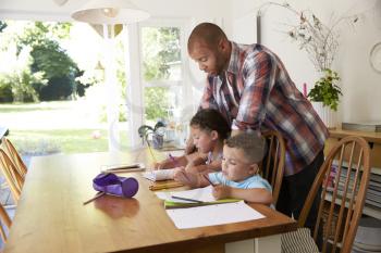 Father Helping Children With Homework At Table