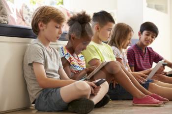 Group Of Children Sit On Floor And Use Technology